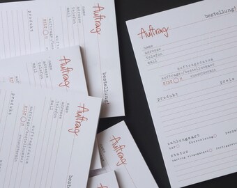 May include: Multiple white order forms with the word "Auftrag" (German for "order") written in red at the top of each form. The forms have fields for name, address, phone number, email, order date, order number, product, price, and payment method.