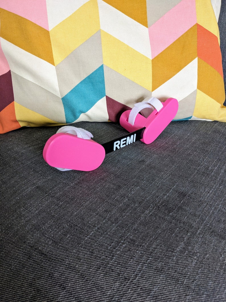 May include: Pink foot and ankle support with adjustable straps and the word "REMI" printed on the black connecting strap.