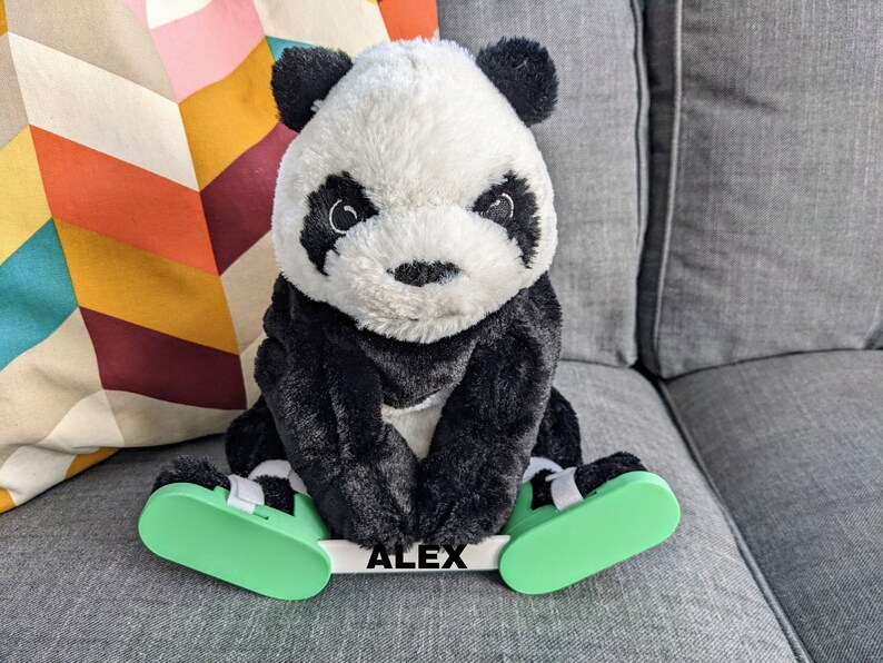 May include: A black and white panda plush toy wearing green and white shoes with the name "ALEX" printed on the front.