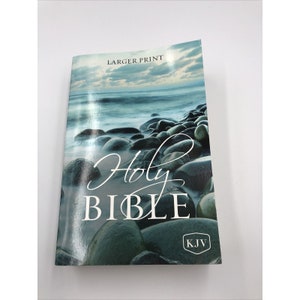 May include: A blue and green Holy Bible book with a beach scene on the cover. The cover has the words "Holy Bible" in white cursive text and "KJV" in a white circle. The text "Larger Print" is at the top of the cover.
