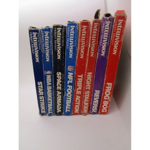 May include: A collection of nine Intellivision game cartridges, including Frog Bog, Reveris, Night Stalker, Triple Action, NFL Football, Space Armada, NBA Basketball, and Star Strike. The cartridges are arranged vertically, with the oldest cartridge at the top and the newest cartridge at the bottom.