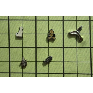 May include: Five silver charms with different designs. The charms include a dog, a monkey, a fish bone, a gnome, and a tail fin.