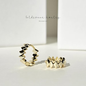 May include: A gold-coloured jewellery set comprising a hoop earring and a ring, both with a repeating geometric pattern. The earrings and ring have a minimalist style. The brand name "Goldspoon Jewelry" and the word "Minimalist" are in the image.