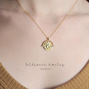 May include: Gold chain necklace with a spinning coin pendant featuring a detailed design. The coin is attached to a delicate gold chain and hangs from a simple gold chain.