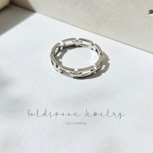 May include: A silver-colored ring with a chain link design. The ring is on a white surface with the text "Goldspoon Jewelry CALIFORNIA" in a handwritten font.
