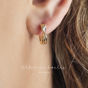 Puede incluir: Pendientes de aro de oro con un diseño trenzado. Los pendientes están hechos de metal dorado brillante.