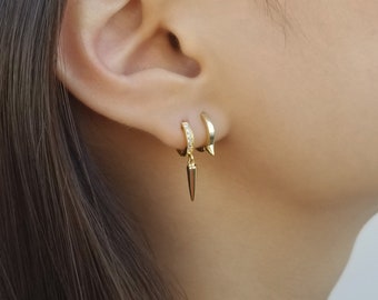 May include: Gold hoop earrings with a small diamond-encrusted hoop and a larger hoop with a dangling spike.