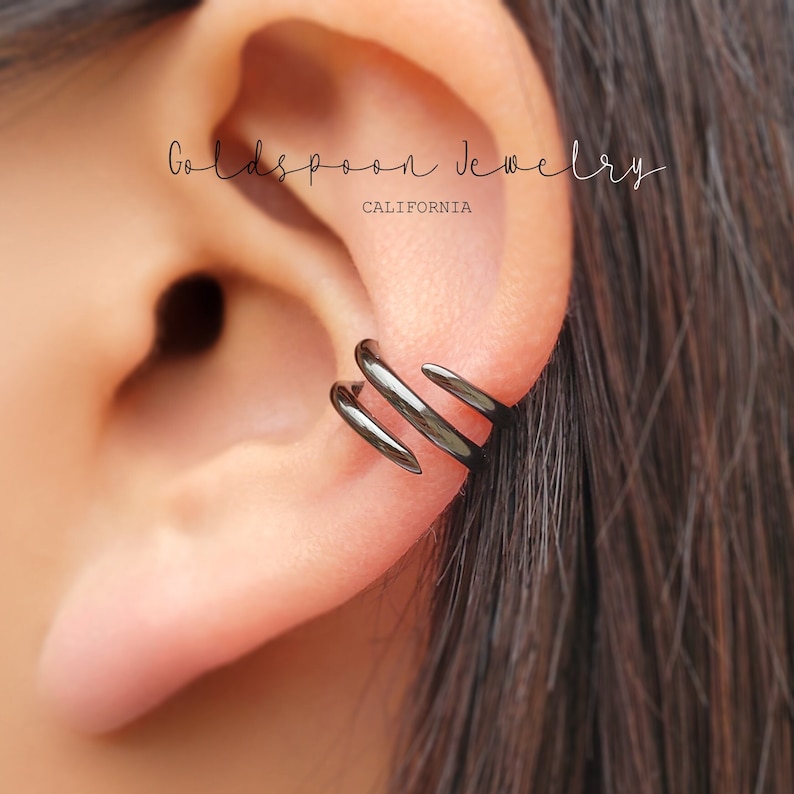 Puede incluir: Un aro para la oreja negro con tres puntas. El aro para la oreja se lleva en la parte superior de la oreja.