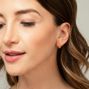 May include: Gold hoop earrings with a honeycomb design. The earrings are small and delicate, and they are perfect for everyday wear.