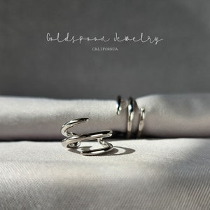 May include: Two silver rings with a twisted design. The rings are on a white fabric background. The text "Goldspoon Jewelry California" is visible at the top of the image.
