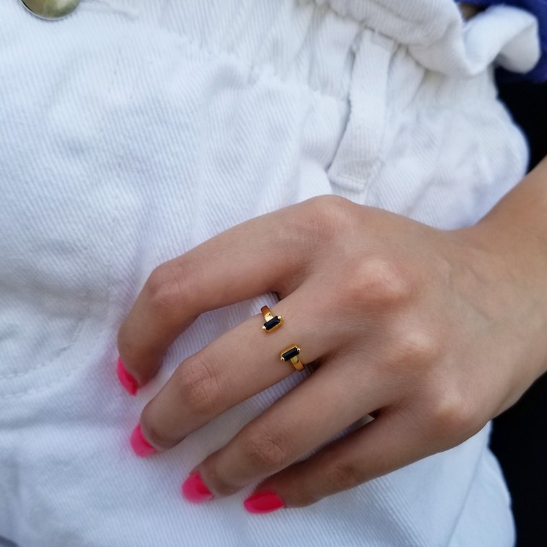 May include: Gold ring with two black rectangular stones. The ring is open and adjustable.
