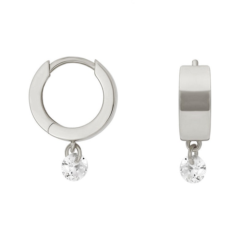 May include: A pair of silver hoop earrings with a small, clear gemstone dangling from each hoop.