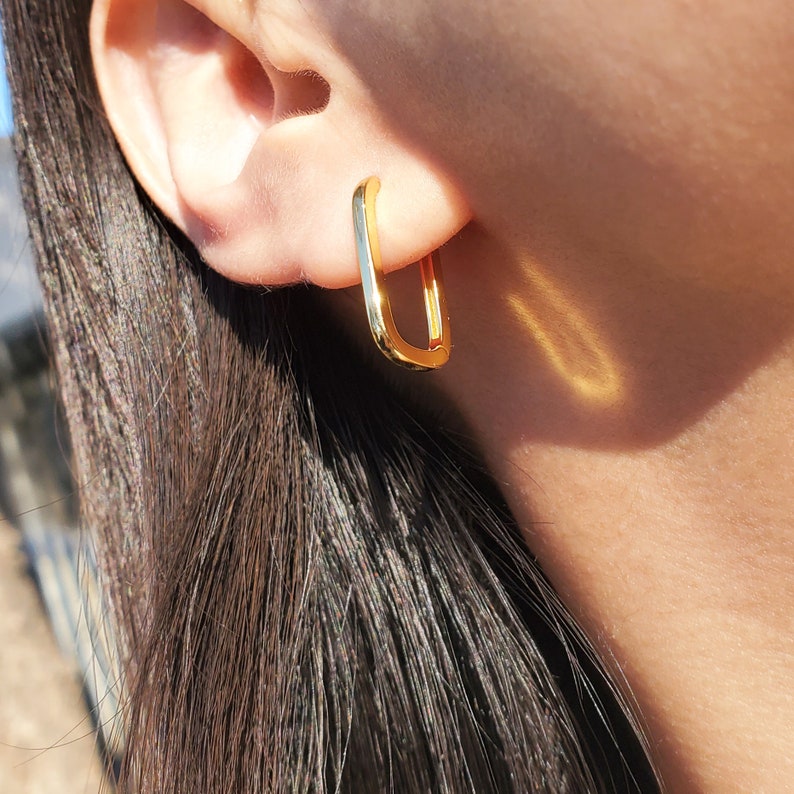 K&ouml;nnte beinhalten: Goldene quadratische Creolen. Die Ohrringe sind schlicht und modern, mit einem eleganten, minimalistischen Design.
