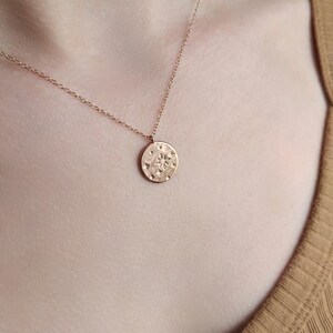 May include: A rose gold necklace with a round pendant featuring a textured design with a star in the center.