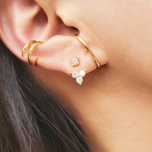 May include: Gold ear cuff with a small, clear crystal stud and a larger, three-stone crystal dangle earring.
