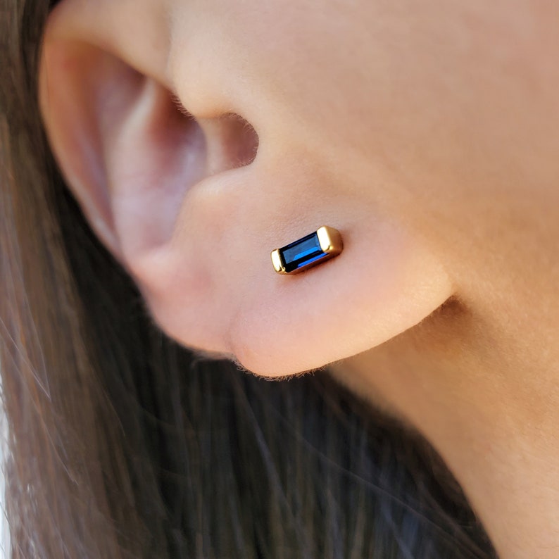 May include: Gold stud earrings with a blue rectangular gemstone.
