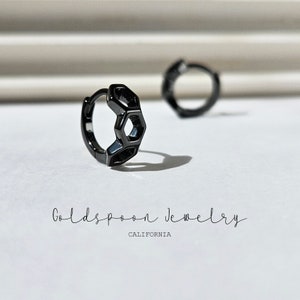 May include: A pair of black hoop earrings with a geometric hexagonal design. The earrings are made of metal and have a polished finish.