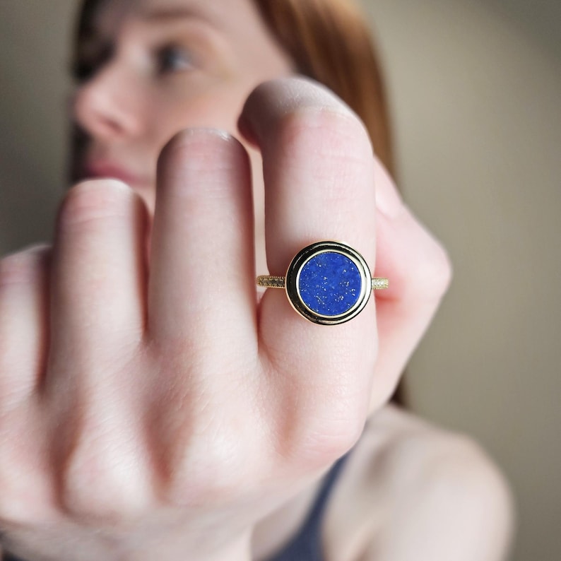 May include: A gold ring with a round blue lapis lazuli stone set in a bezel setting.