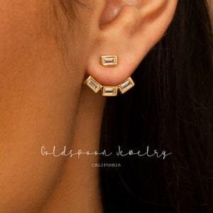 Puede incluir: Pendientes de aro de oro con piedras de circonita cúbica transparentes. Los pendientes tienen forma de media luna y están diseñados para llevarse en la parte superior de la oreja. Los pendientes están hechos de metal chapado en oro y están disponibles en una variedad de tamaños.