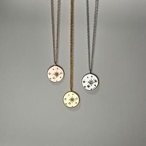 May include: Three gold necklaces with star-shaped pendants. The pendants are adorned with small diamonds and a larger center stone. The necklaces are on a white background.