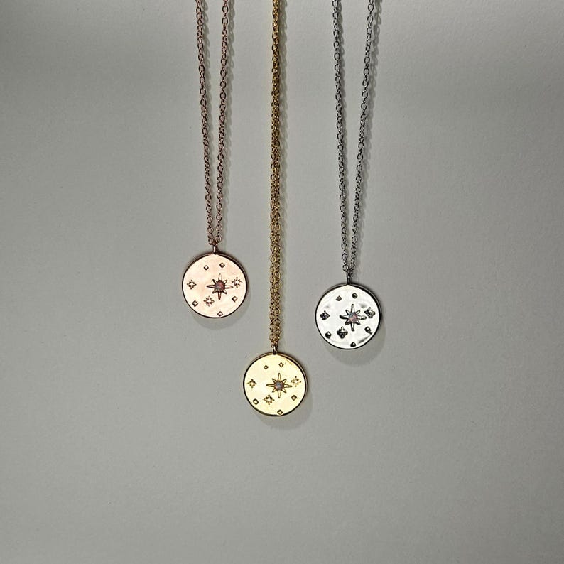 May include: Three gold necklaces with star-shaped pendants. The pendants are adorned with small diamonds and a larger center stone. The necklaces are on a white background.