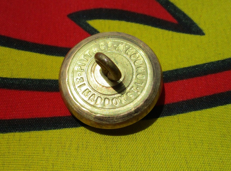 Antique Livery Button of a deer hart stag holding an arrow with two shells Pitt
