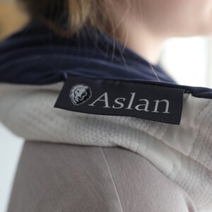 May include: A close-up of a navy blue and white hooded garment with a black label that reads "Aslan".