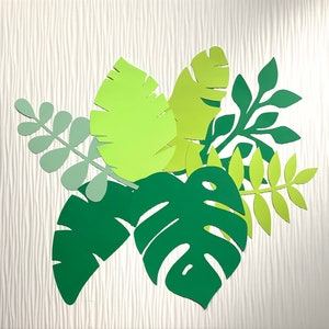 May include: A collection of paper cutouts of green and yellow leaves. The leaves are arranged in a cluster, with the largest leaf in the center. The leaves are all different shapes and sizes.