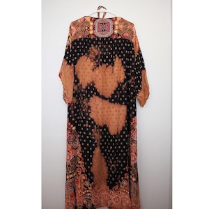 May include: A long, flowing black and orange patterned robe with a tie closure. The robe has a tie closure and a paisley pattern.
