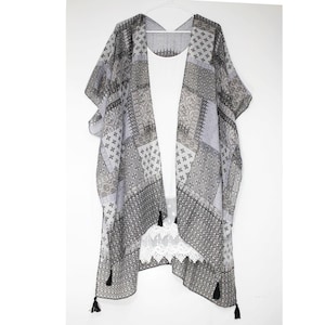 May include: A gray and black patterned sheer kimono with black tassels and a white lace trim.