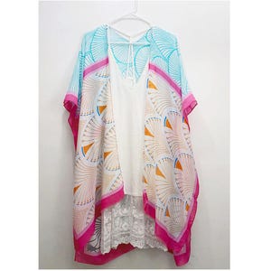 Puede incluir: Un kimono estampado en blanco y azul con ribetes rosas. El kimono está hecho de una tela ligera y tiene un corte holgado. Presenta un escote en V y mangas cortas.