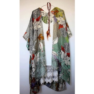 May include: A floral print kimono with a white tank top underneath. The kimono has a green, white and orange floral pattern. The tank top has a lace trim.