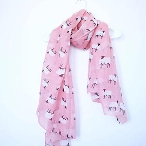May include: A pink scarf with a white sheep pattern.