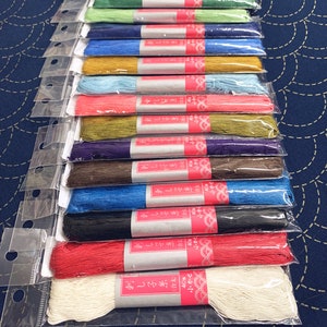 Op de afbeelding: Een verzameling van 16 spoelen borduurgaren in verschillende kleuren, waaronder rood, blauw, groen en wit. Elke spoel is gelabeld met Japanse tekst en de woorden "刺し子糸" en "40m".