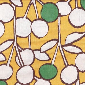 Puede incluir: Una tela amarilla con un patrón repetitivo de círculos blancos y verdes. Los círculos están delineados en marrón y el fondo es amarillo sólido.