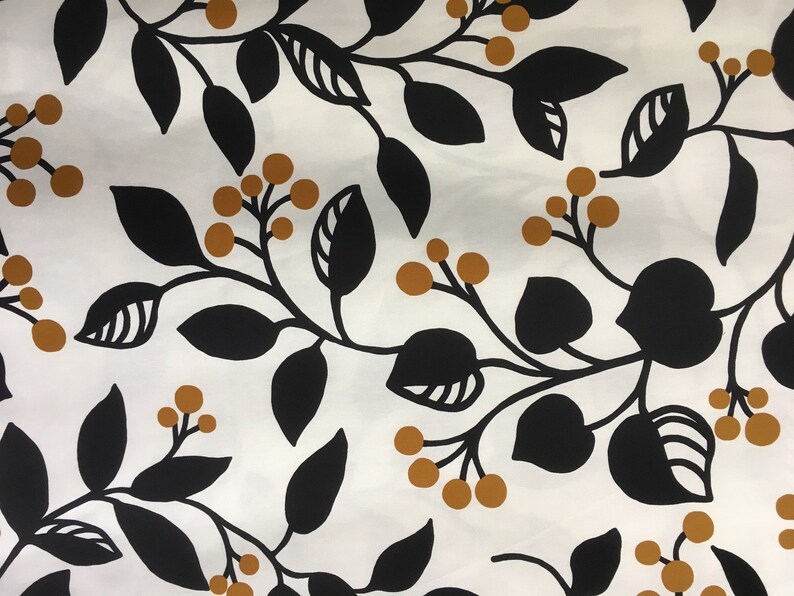 May include: White fabric with a repeating pattern of black leaves and stems, and small, round, golden-brown berries. The design is a botanical or floral print, suitable for textiles or wallpaper.