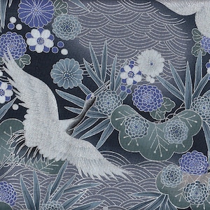 Op de afbeelding: Een blauw en wit bloemenpatroon met een witte kraanvogel die door het patroon vliegt. De achtergrond is donkerblauw met een golfpatroon.