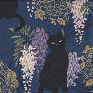 Könnte beinhalten: Eine schwarze Katze sitzt auf einem blauen Hintergrund mit einem floralen Muster. Die Blumen sind rosa, lila und goldfarben. Die Katze hat einen ernsten Ausdruck.