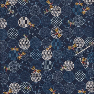 Könnte beinhalten: Marineblauer Stoff mit einem sich wiederholenden Muster aus Kreisen in verschiedenen Blau- und Weißtönen. Jeder Kreis enthält ein anderes geometrisches Design und ist mit einer Libelle akzentuiert.