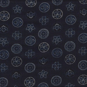 Könnte beinhalten: Dunkelblauer Stoff mit einem sich wiederholenden Muster aus weißen und hellblauen Blumen- und geometrischen Designs. Das Muster umfasst stilisierte Blumen, Kreise und Sternformen und erzeugt eine strukturierte, dekorative Oberfläche.