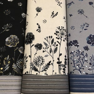 May include: Three rolls of fabric with floral designs. The fabric on the left is black with gold highlights, the middle is off-white, and the right is grey. Each has a border of horizontal stripes.