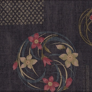 Könnte beinhalten: Dunkelmarinefarbener Stoff mit floralen Mustern. Das Design zeigt stilisierte Blumen in Rosa und Creme mit grünen und blauen Akzenten, angeordnet in kreisförmigen und quadratischen Motiven. Der Hintergrund hat ein strukturiertes Aussehen.