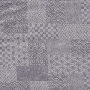 Op de afbeelding: Een grijze stof met een patchwork-ontwerp met verschillende Japanse patronen. Het ontwerp omvat geometrische vormen, zoals vierkanten, zeshoeken en golfachtige motieven, waardoor een gestructureerd en visueel interessant oppervlak ontstaat.