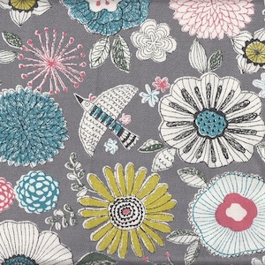 May include: A gray fabric with a repeating pattern of colorful flowers, birds, and leaves. The flowers are in shades of blue, yellow, pink, and white. The birds are white with blue accents. The leaves are green.