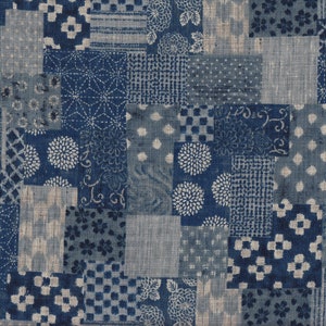 Op de afbeelding: Een patchwork-ontwerp met blauwe en grijze stoffen vierkanten. De vierkanten tonen diverse patronen, waaronder bloemen, stippen en geometrische motieven. De algehele esthetiek is een mix van traditionele en moderne stijlen, geschikt voor textiel of decoratieve items.