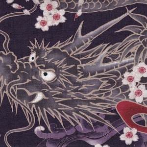 Könnte beinhalten: Nahaufnahme eines schwarzen und grauen Drachenmusters auf einem violetten Stoff. Das Gesicht des Drachen ist deutlich zu sehen, mit scharfen Zähnen und einem großen Auge. Der Stoff ist mit weißen Blüten mit roten Zentren verziert.