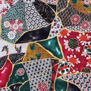 Op de afbeelding: Een kleurrijk patchwork-ontwerp met Japanse patronen. De stof toont een verscheidenheid aan vormen en kleuren, waaronder rood, groen, goud en zwart. Bloemen- en geometrische motieven zijn prominent aanwezig, met gouden lijnen die de secties scheiden.