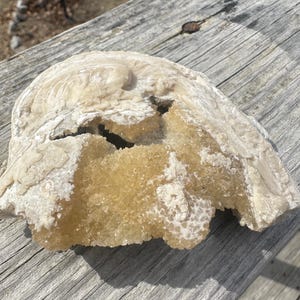 May include: A broken, white, and yellow rock with a crystalline texture. The rock has a rough, uneven surface and appears to be a natural formation.
