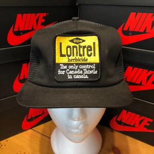 May include: Black trucker hat with a yellow patch that reads "DOW Lontrel herbicide The only control for Canada Thistle in canola."