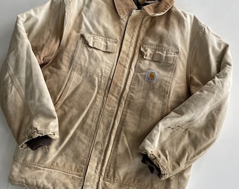 Puede incluir: Una chaqueta de trabajo Carhartt desgastada, de color beige, con cuello de pana marrón y un parche con el logotipo de Carhartt en el pecho izquierdo.